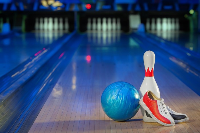Bowling ball, pin, and shoes on lane