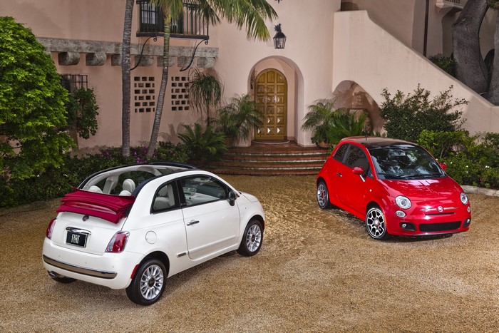 Two Fiat 500 cars parked in front of a building