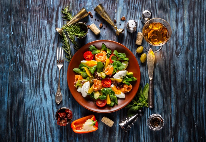 Salad with salmon, eggs, and cheese on a plate with wine