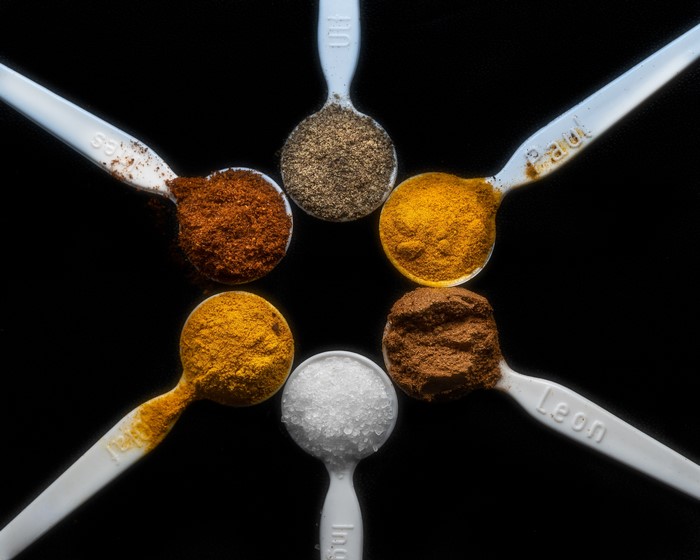 Spices in spoons on black background