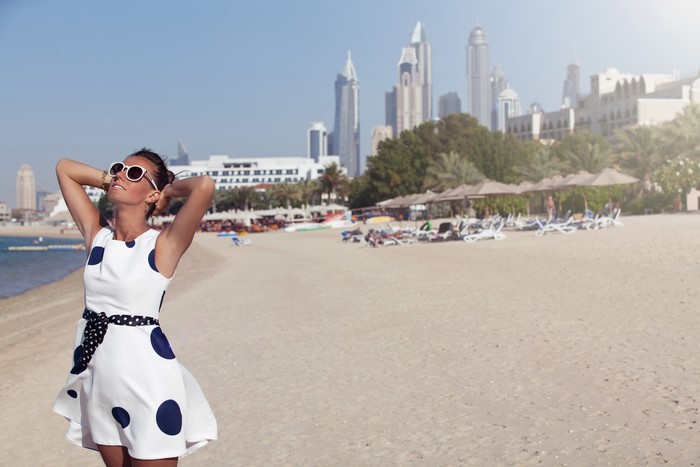 Woman in polka dot dress on a beach with city skyline