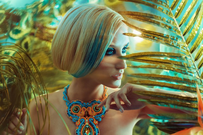 Woman with blonde hair and blue streaks wearing a colorful necklace