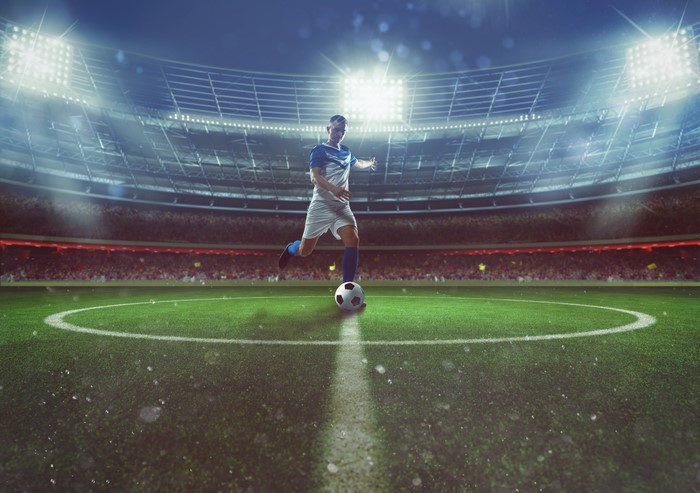 Man in uniform kicking soccer ball in stadium