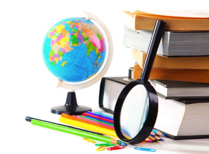 Globe, magnifying glass, books, and pencils on white background
