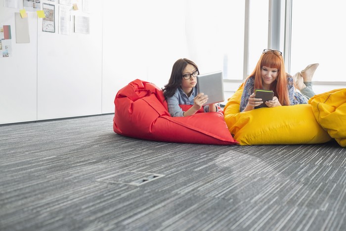 Two women using tablets on beanbag chairs