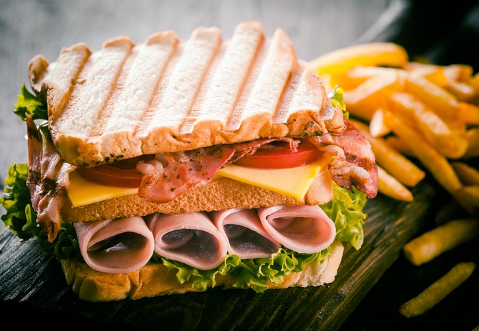 Sandwich with ham, bacon, cheese, tomato, lettuce, and french fries