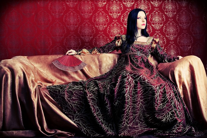 Woman in Renaissance Dress with Fan on Couch