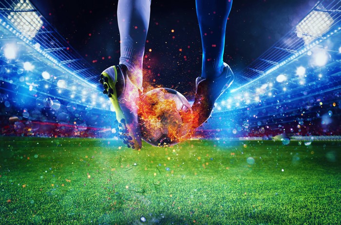 Soccer ball on fire between two players' legs in stadium