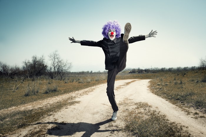 Clown kicking leg up on dirt road