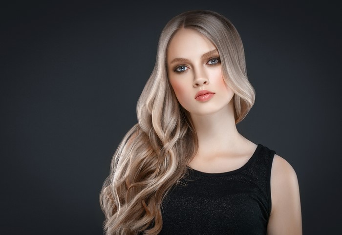 Blonde woman with wavy hair on gray background