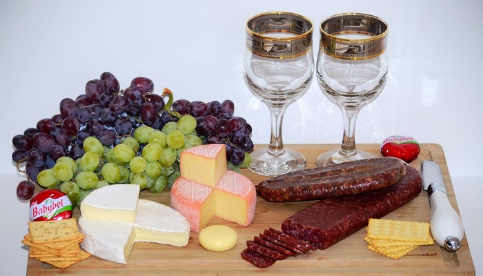 Cheese, Grapes, Sausage, Crackers, and Stemware on a Cutting Board