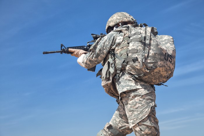 Soldier aiming assault rifle with backpack