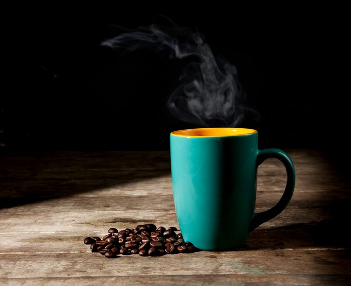 Coffee cup with steam and coffee beans