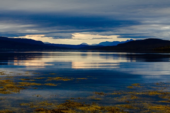 Mountains reflecting in a calm bay at dusk in Norway