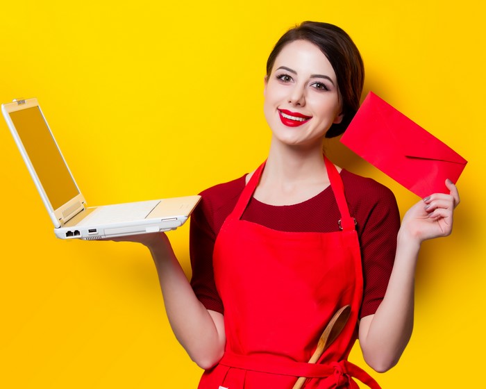 Woman in red apron holding laptop and red envelope