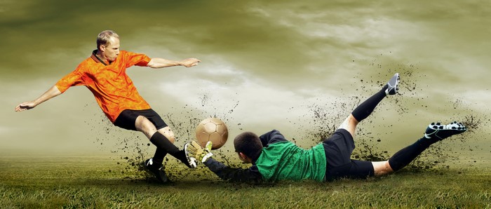 Soccer player kicking ball, goalkeeper diving