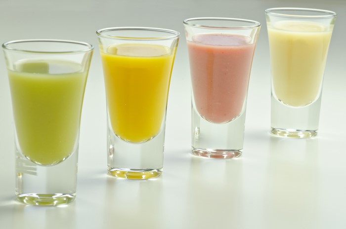 Four shot glasses with colorful drinks