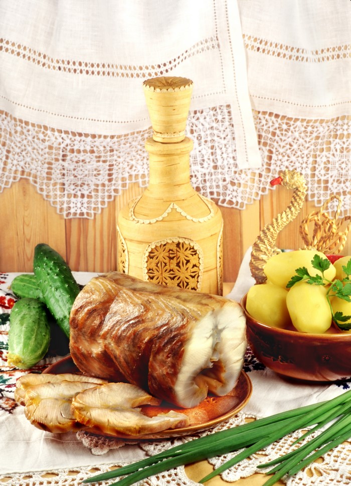 Smoked fish with potatoes, cucumbers, and a birch bark bottle