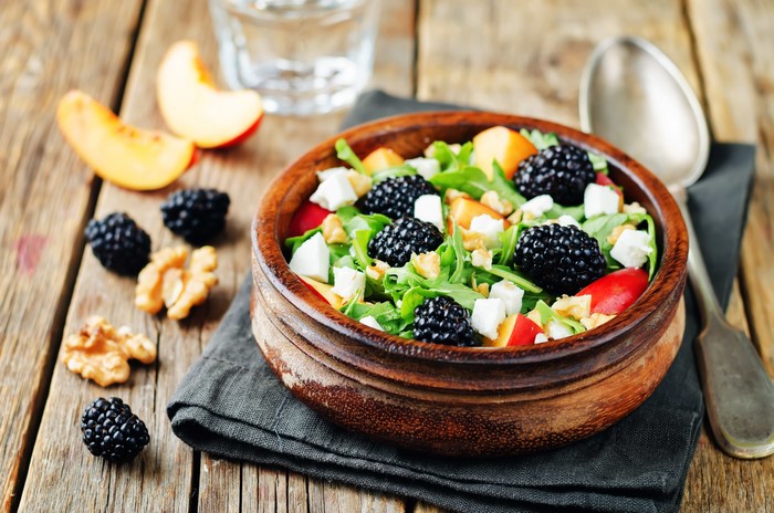 Salad with blackberries, peaches, feta, and walnuts in a bowl