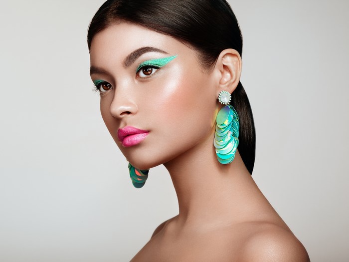 Brunette girl with vibrant makeup and large earrings