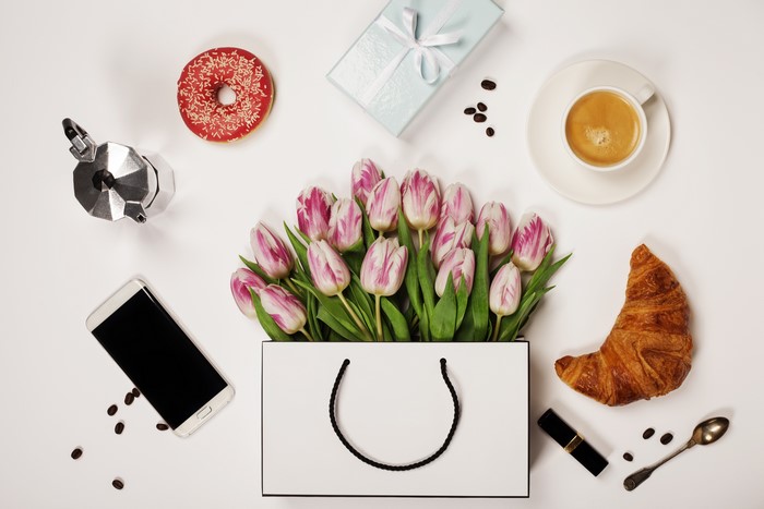 Tulips in a handbag with coffee, croissant, donut, gift, phone, and moka pot