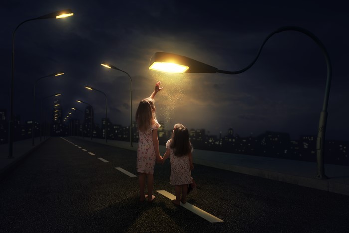 Two little girls reaching for street light at night
