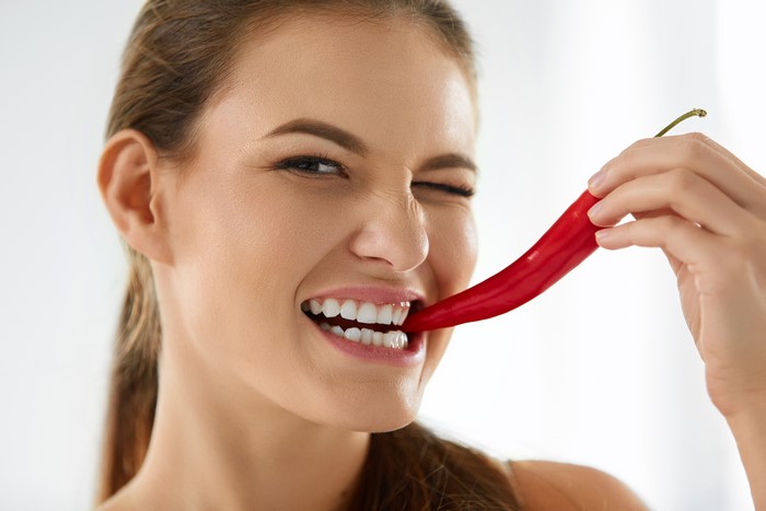 Woman biting a red chili pepper