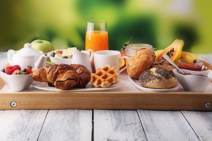 Breakfast tray with croissants, buns, juice, and fruit