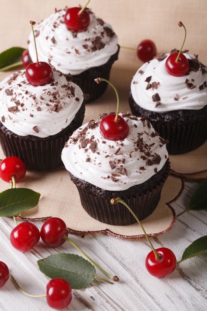 Chocolate cupcakes with white frosting and cherries