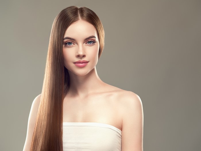 Woman with long brown hair against gray background