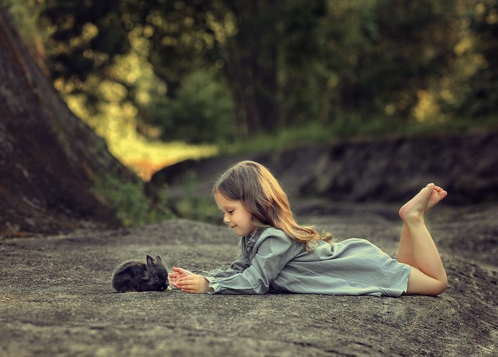 Girl lying down with a rabbit on rocks
