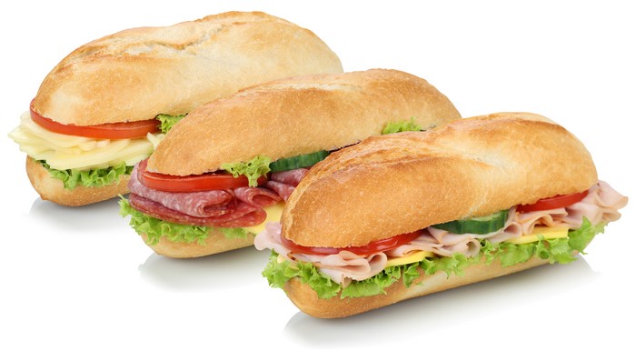 Three sandwiches with sausage, cheese, and vegetables