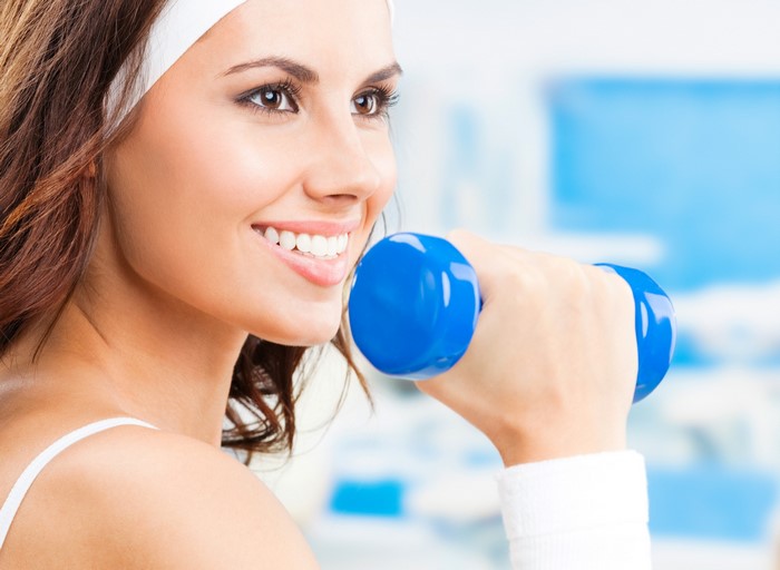 Woman smiling while holding a dumbbell