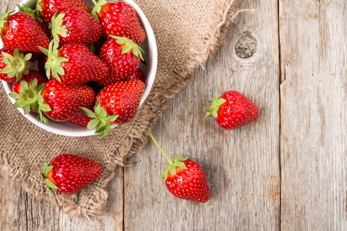 Strawberries in a bowl on wood planks