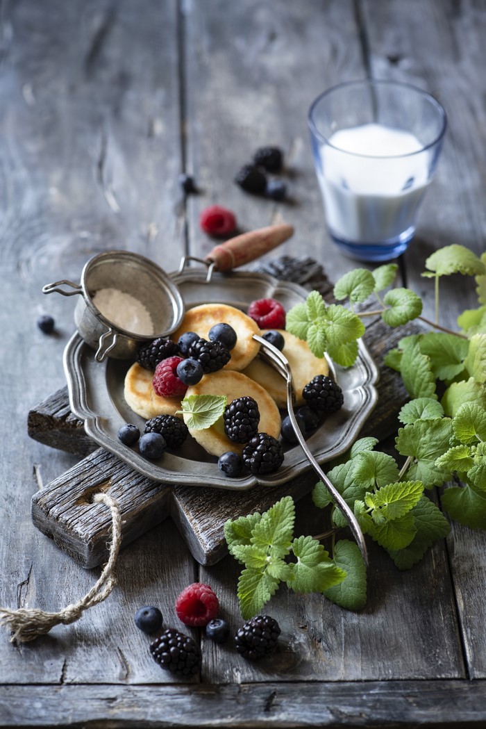 Pancakes with berries and milk on a wooden board