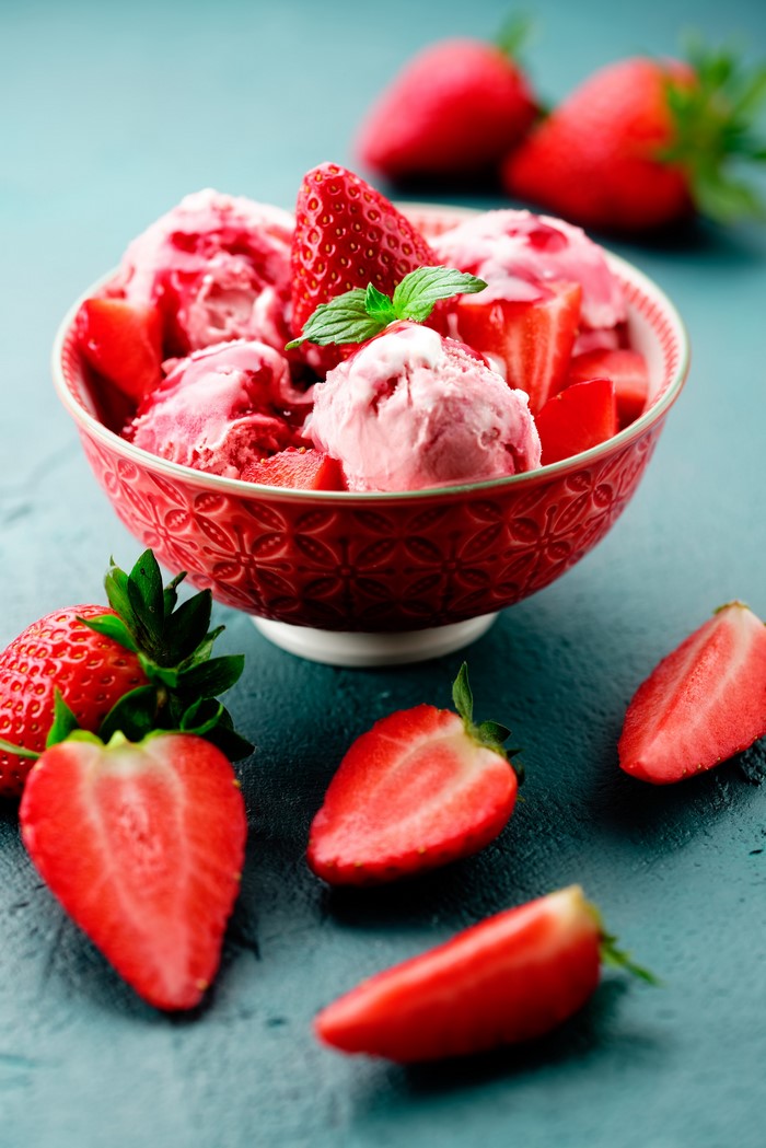 Strawberry ice cream in a bowl with fresh strawberries