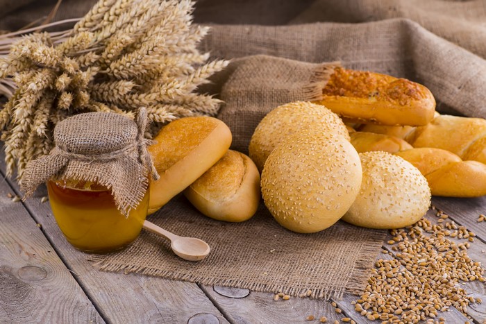 Honey Jar with Buns and Wheat on Wood