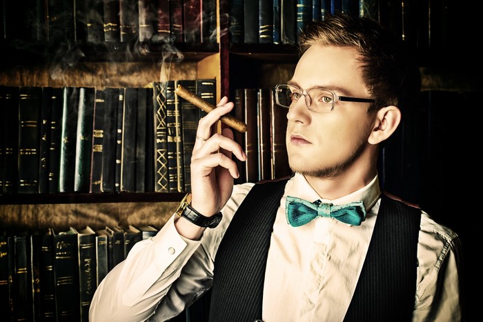 Man with glasses smoking cigar in library