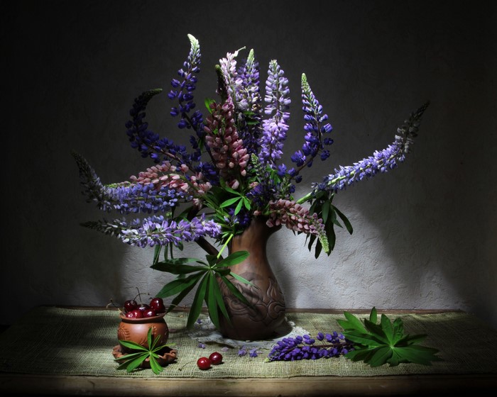 Still life with lupines and cherries in a vase