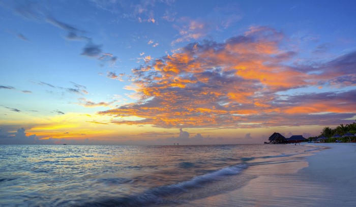 Sunset over the ocean with clouds and beach huts