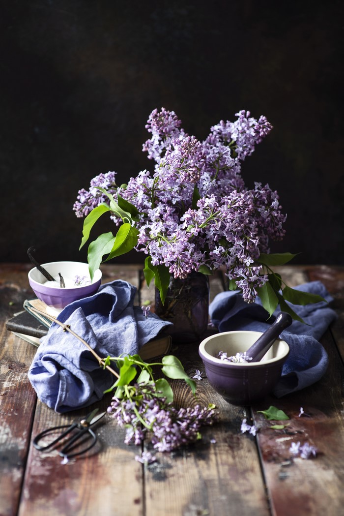 Lilacs in a vase with mortar and pestle on wood