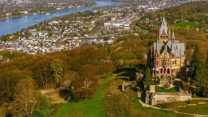 Drachenburg Castle overlooking a town and river in Germany
