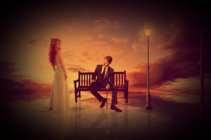 Man and woman on bench with lantern at sunset