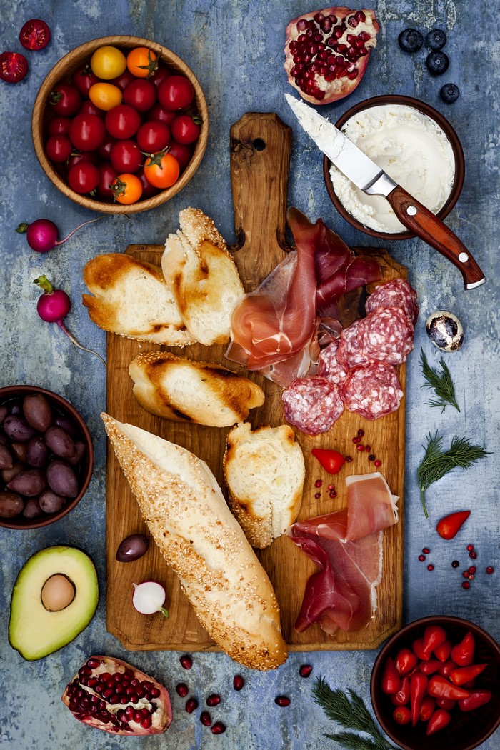 Charcuterie board with bread, meats, cheese, and fruits