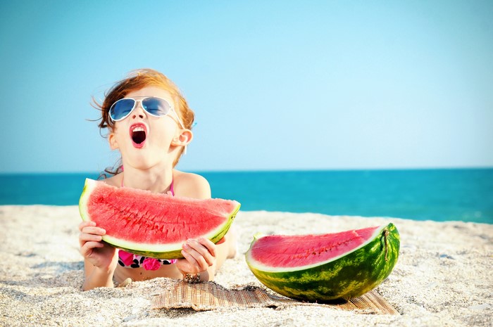 Girl eating watermelon on the beach