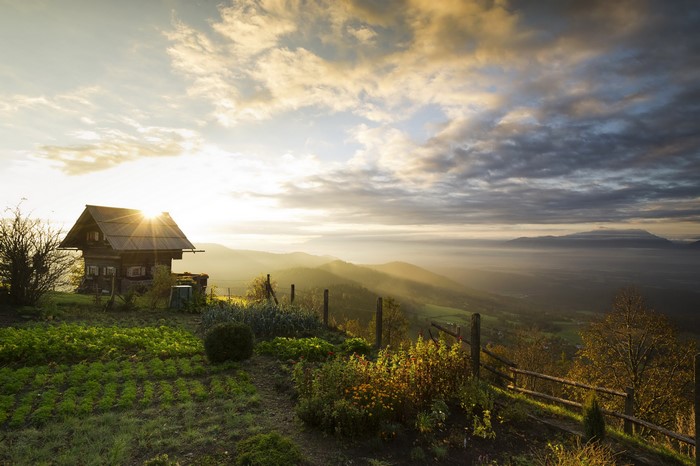 Wooden house on a hill at sunrise with mountain view