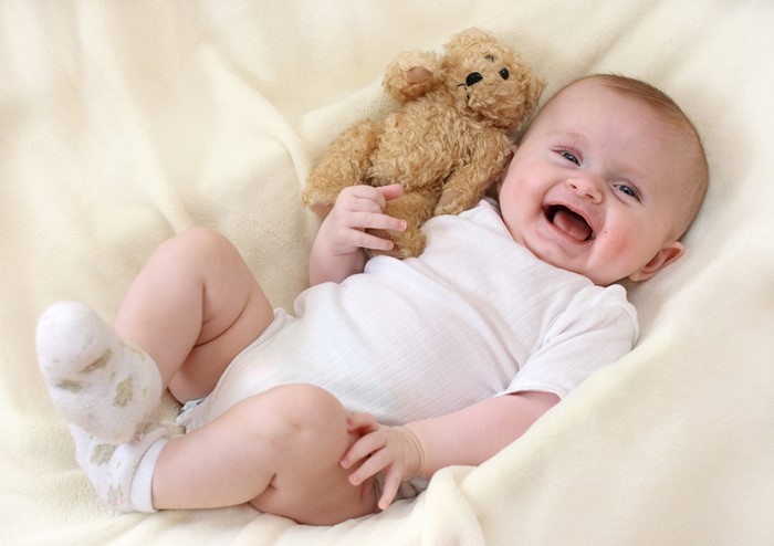 Baby laughing with a teddy bear
