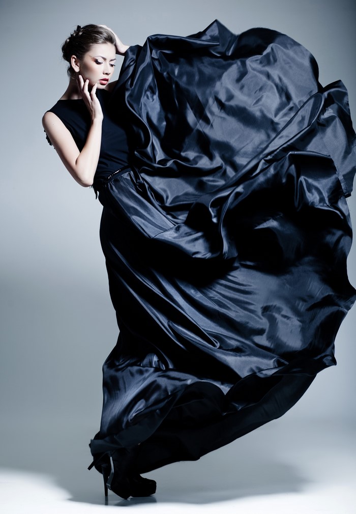 Woman in flowing black dress on gray background