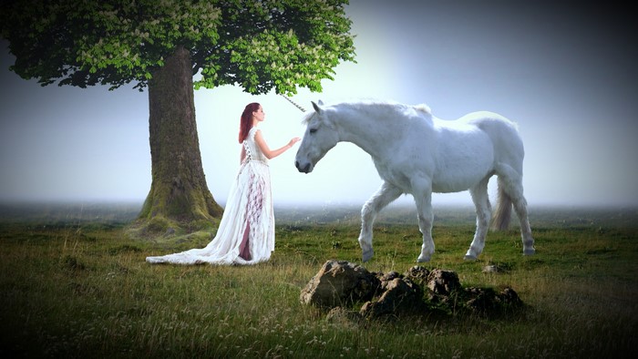Woman in white dress with unicorn under tree
