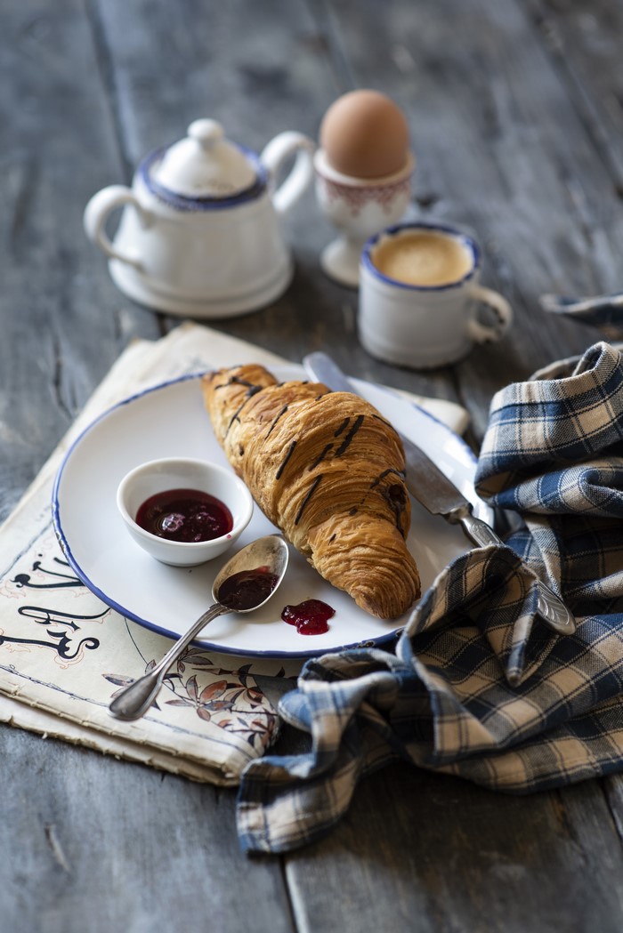 Croissant with jam, coffee, and boiled egg for breakfast